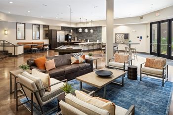 A spacious living room with a variety of seating options and a kitchen area